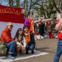 A family posing for a picture on the Amstelveld flea market on King's Day 2023.