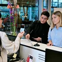 Woman and man at the desk at the INAmsterdam offices. Employee checking id card