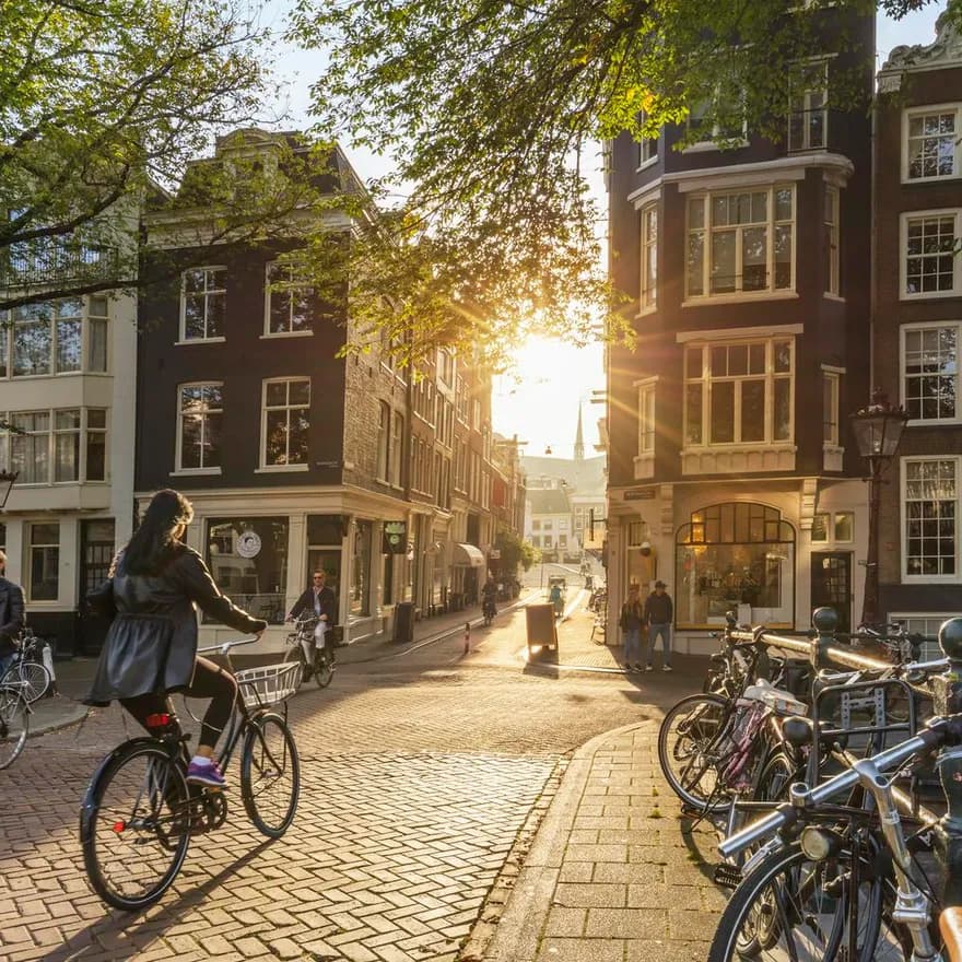 Amsterdam, Netherlands - September 22, 2021: Early morning in Amsterdam. Artistic image. People ride bicycles, the ancient European city of Amsterdam. Sunlight and silhouettes, beautiful downtown houses. Amsterdam, Holland, Netherlands, Europe