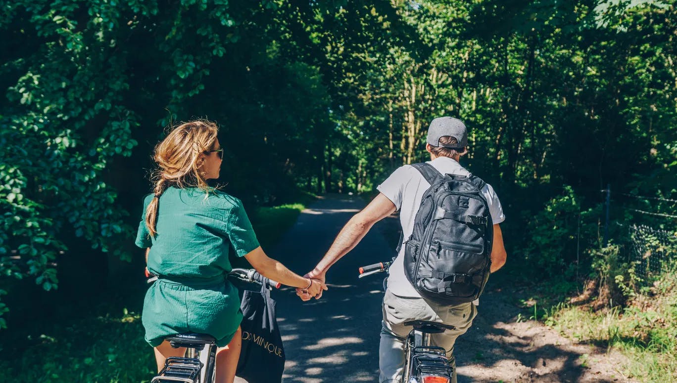 Couple cycling in the park holding hands