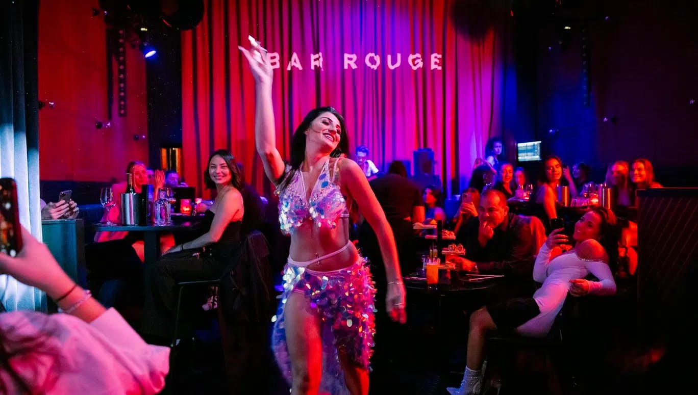 Bar Rouge, interior with drinks and people in the bar, woman giving a show dancing and people smiling