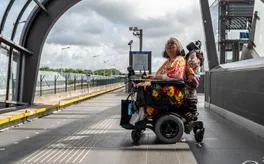 A person in an electric wheelchair on the platform waiting for the metro.