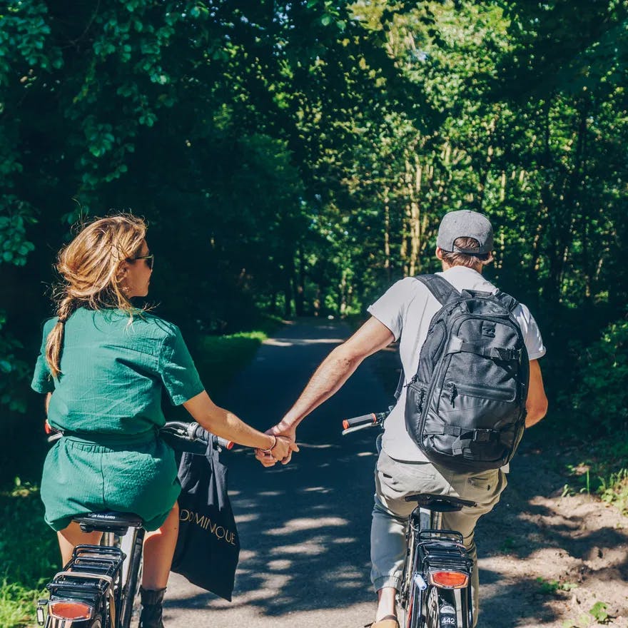 Couple cycling in the park holding hands