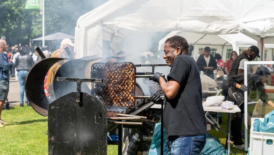 A man is grilling chicken during Keti Koti Festival 2022 in the Oosterpark.
