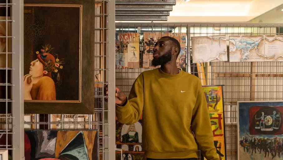 A man looks at the different paintings and drawings of the art loan of CBK Zuidoost.