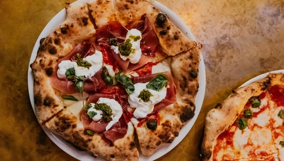 pizza topped with ham and burrata