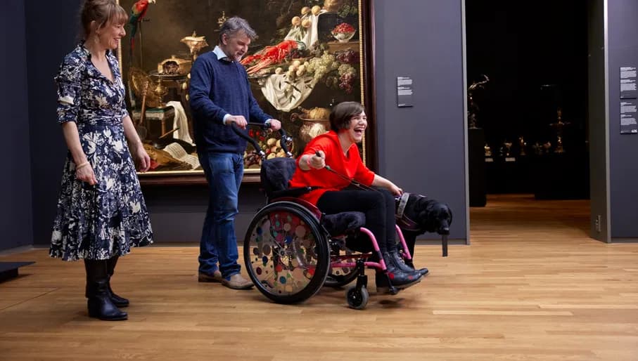 Happy woman in a wheelchair and a dog, visiting Rijksmuseum