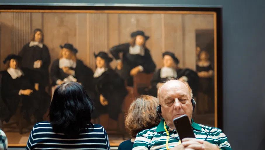 A man is listening to the audio tour in the Rijksmuseum.