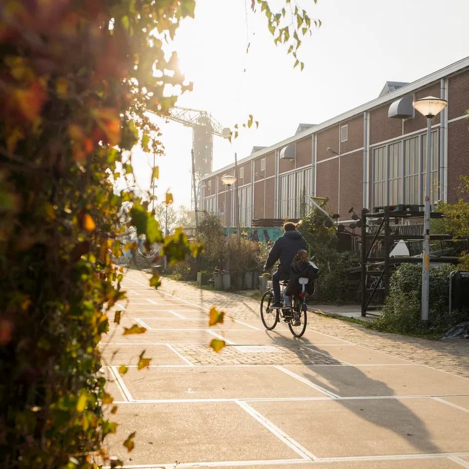 A parent cycling with his child over a sunny Scheepsbouwkade during early autumn.