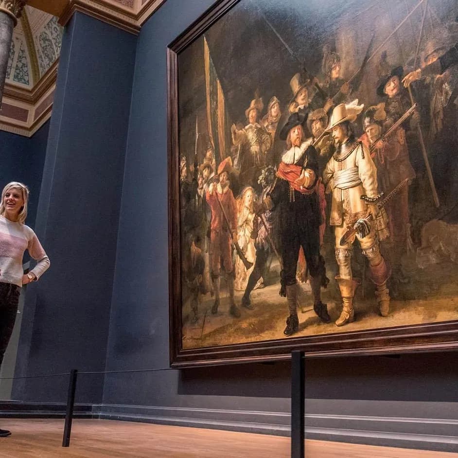 Three women gathered around Rembrandt's Nachtwacht (Nightwatch) painting in the Rijksmuseum.