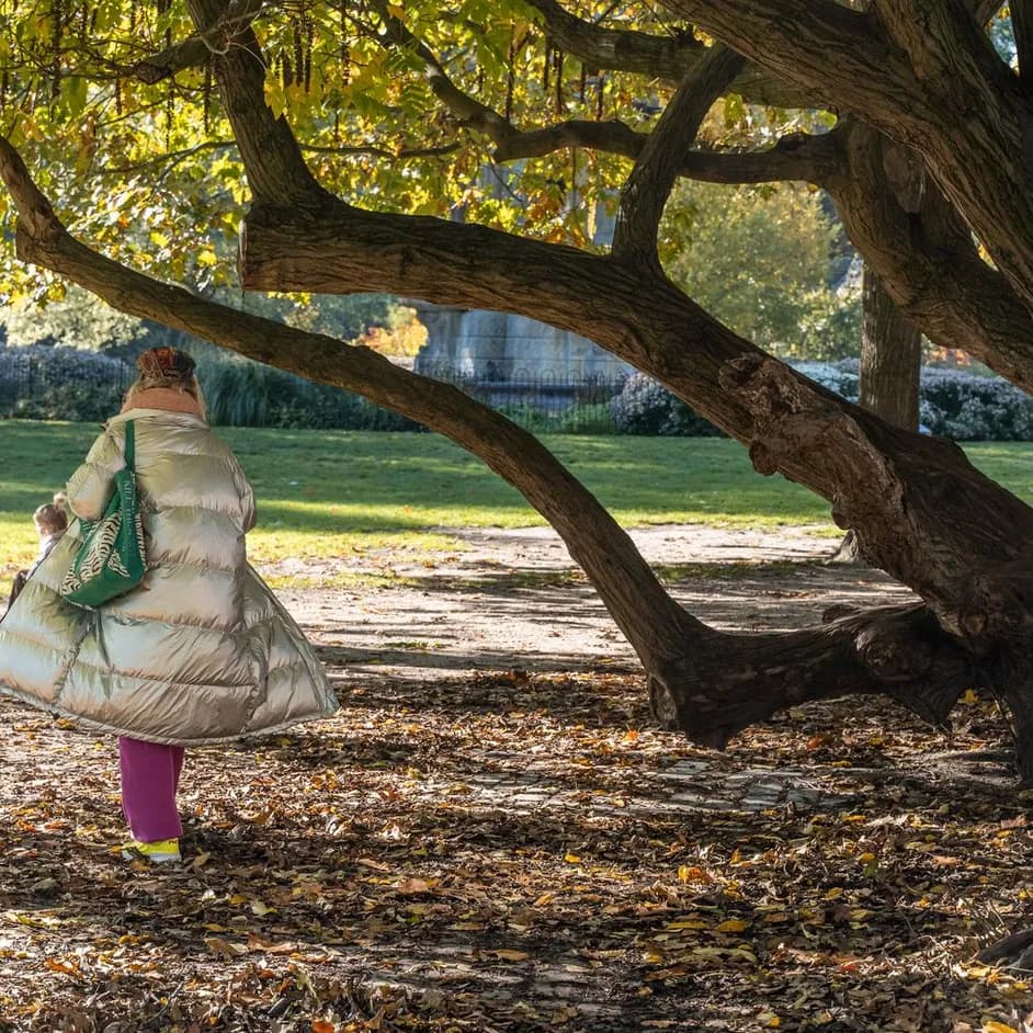 A person walking through the Sarphatipark on a sunny autumn day.