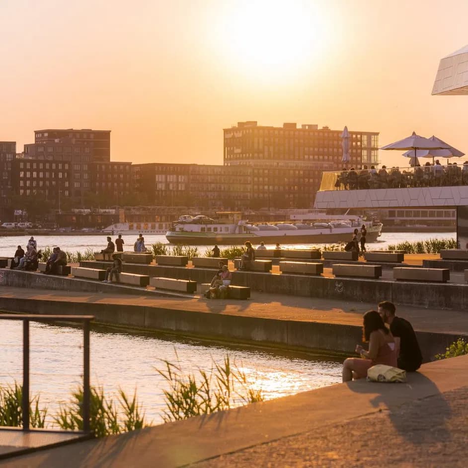 People enjoy the sunset at IJ-boulevard near EYE Filmmuseum.