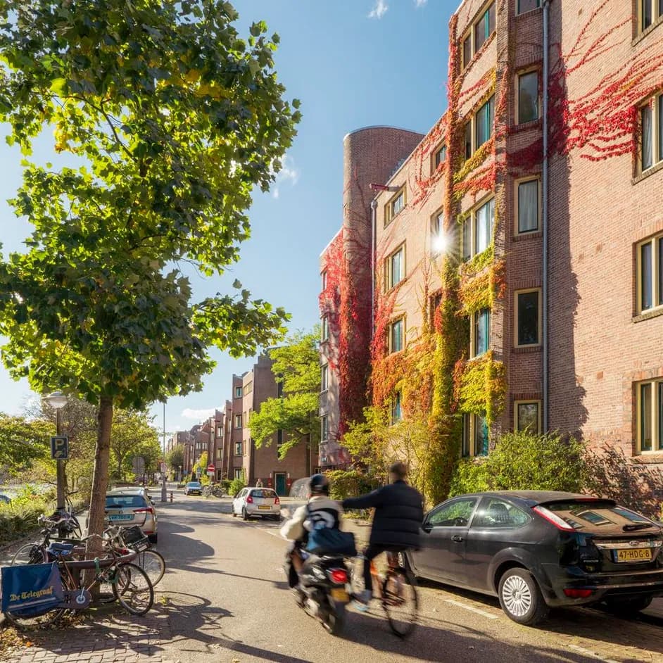 A cyclists hitches a ride with a scooter on Amstelkade.