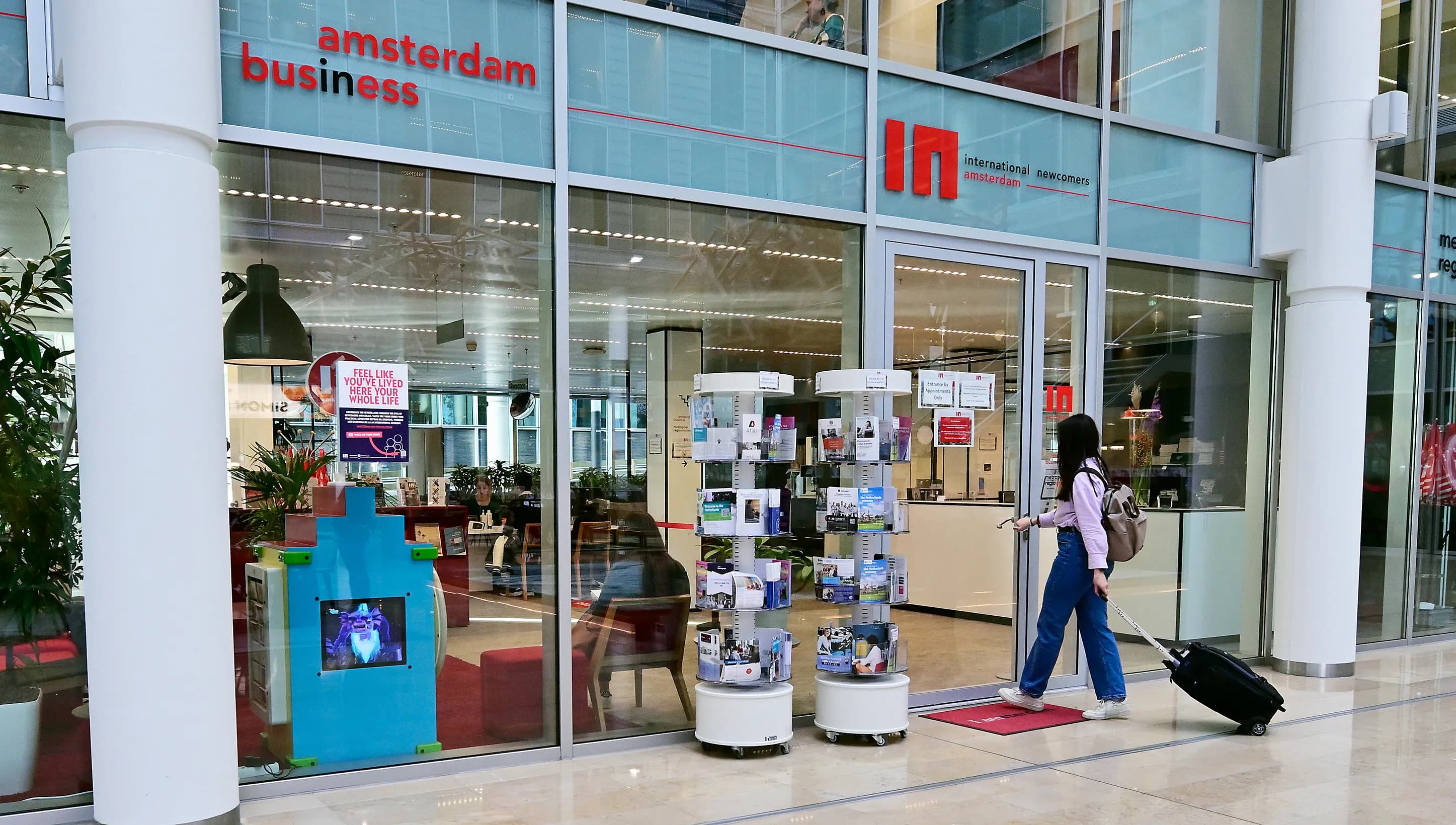 Woman with suitcase walking into the offices of INAmsterdam