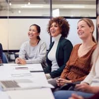 Line Of Businesswomen In Modern Office Listening To Presentation By Colleague