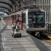A person in an electric wheelchair riding on the metro platform.