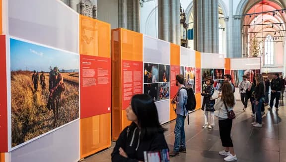 Visitors looking at photos in exhibition at World Press Photo 2023 in De Nieuwe Kerk