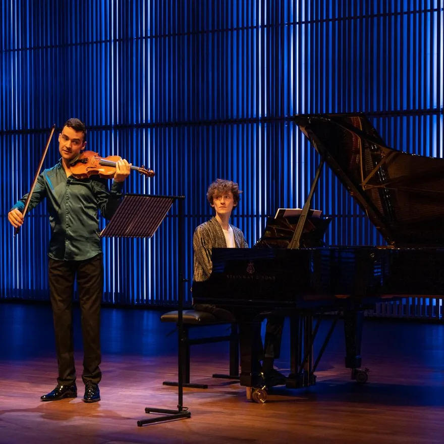 A violinist and a pianist on stage in het Muziekgebouw aan 't IJ