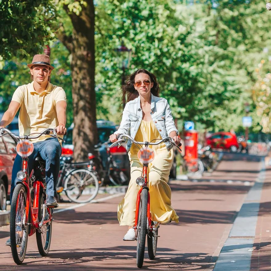 Young happy couple on red bikes cycling on the old streets in the city centre.