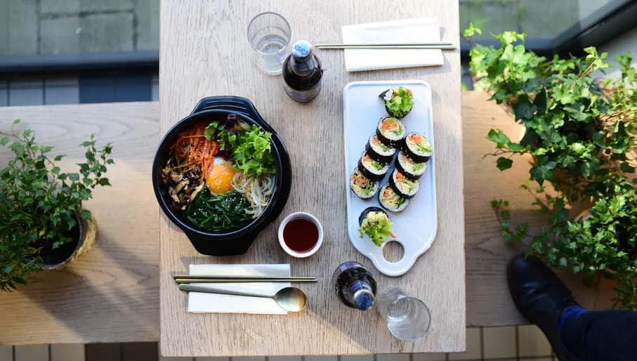 A display of a plate of salad sushi and drinks The Bab Korean restaurant