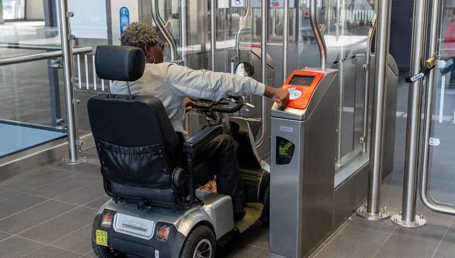 A person in an electric wheelchair checking out in order to exit metro station Noord.