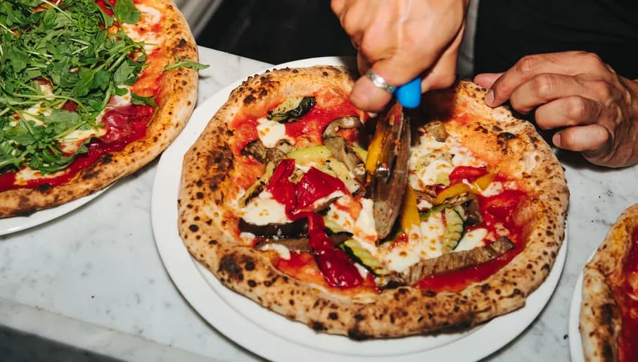 Pizza Beppe restaurant someone cutting pizza
